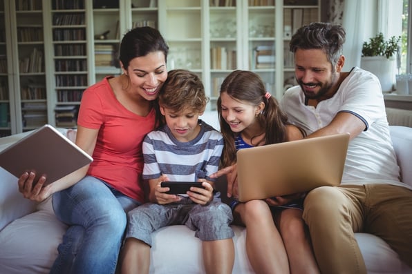 Happy family sitting on sofa and using laptop, mobile phone and digital tablet at home.jpeg